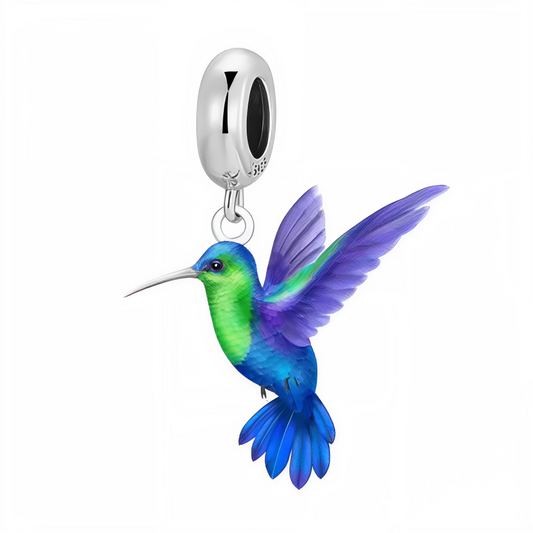 Apportez une touche de légèreté et de couleur à votre collection avec ce charm pendentif en argent 925 représentant un colibri délicat. Son corps finement émaillé en bleu et vert se marie harmonieusement avec ses ailes aux nuances violettes éclatantes, capturant la beauté et la grâce de ce petit oiseau en plein vol. Un bijou vibrant et raffiné, parfait pour les amoureux de la nature et de la liberté.