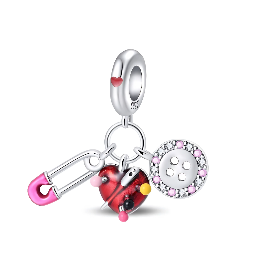 Ce charm pendentif en argent réunit trois mini breloques de couture : une épingle de sûreté rose, un cœur façon pelote à épingles rouge et noir, et un bouton rond bordé de cristaux roses et clairs. La bélière lisse décorée d’un petit cœur rouge apporte une touche tendre, parfaite pour symboliser la passion de la couture, du DIY ou des travaux d’aiguille.