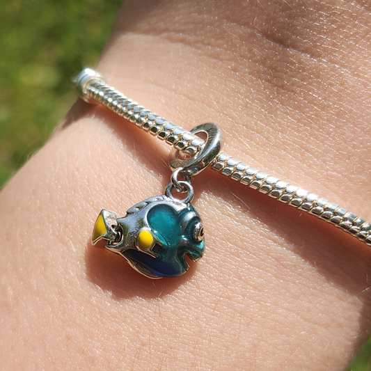 Plongez dans l'univers sous-marin avec le Charm - Dory, inspiré du célèbre personnage de Pixar. Ce charm en argent sterling S925 représente la sympathique et inoubliable Dory, avec ses couleurs bleues et jaunes éclatantes. Idéal pour les amateurs de "Le Monde de Nemo" et "Le Monde de Dory", ce charm apportera une touche amusante et colorée à votre bracelet.
