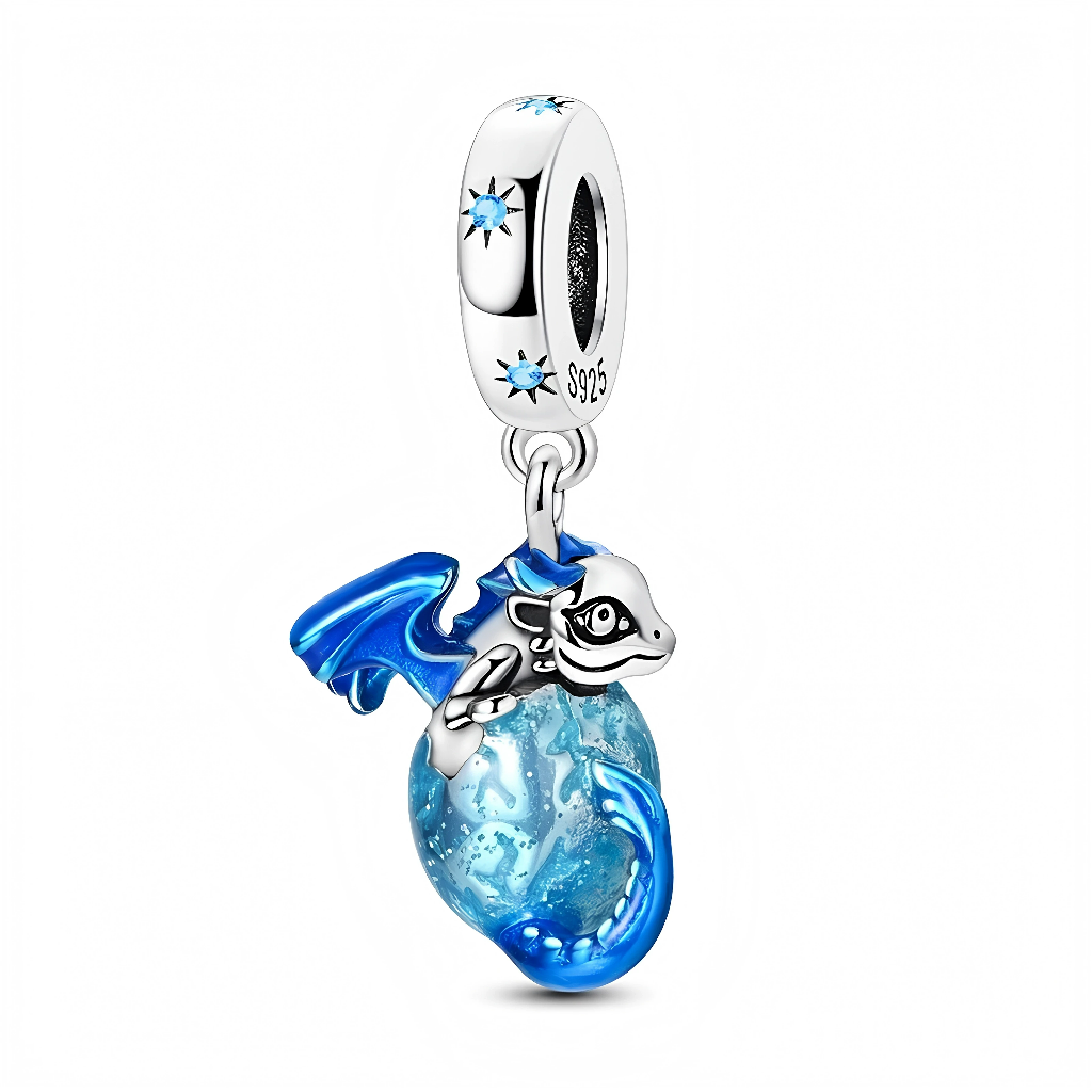La bélière en argent est décorée de petites étoiles serties de cristaux bleus, comme un ciel nocturne au-dessus de la scène. Suspendu en dessous, un baby dragon argent et émail bleu enlace un globe en verre bleu moucheté d’éclats plus clairs, donnant l’impression de tenir entre ses griffes une petite planète ou une sphère d’énergie. Ce bijou onirique évoque la protection, la puissance et l’imaginaire des mondes fantastiques, idéal pour un bracelet à thème dragons ou contes de fées.