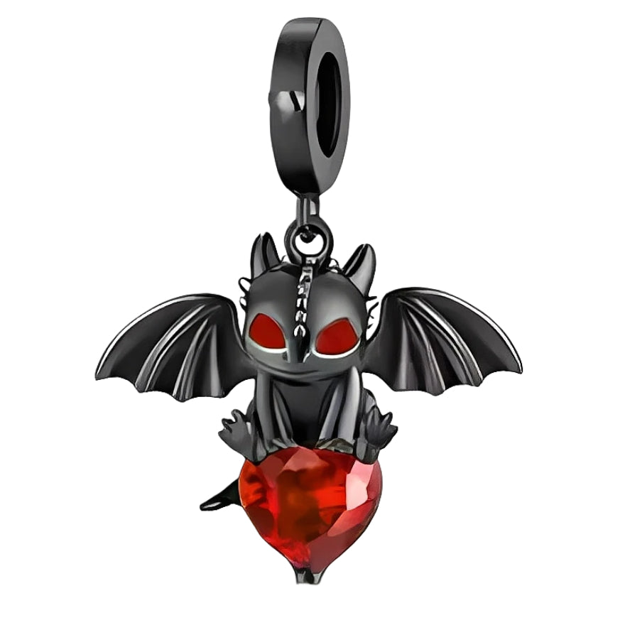 Ce charm pendant en métal noirci met en scène un petit dragon aux grandes ailes déployées, aux yeux rouges flamboyants qui lui donnent un air malicieux et protecteur. Assis, il enlace un cœur en cristal rouge facetté qui capte intensément la lumière, pour une touche à la fois dark et passionnée sur le bracelet.

Caractéristiques :

- Matière : Alliage métal noirci avec cristal synthétique rouge.
- Design : Petit dragon ailé tenant un cœur facetté, suspendu à une bélière lisse.
- Coloris : Noir graphite, rou