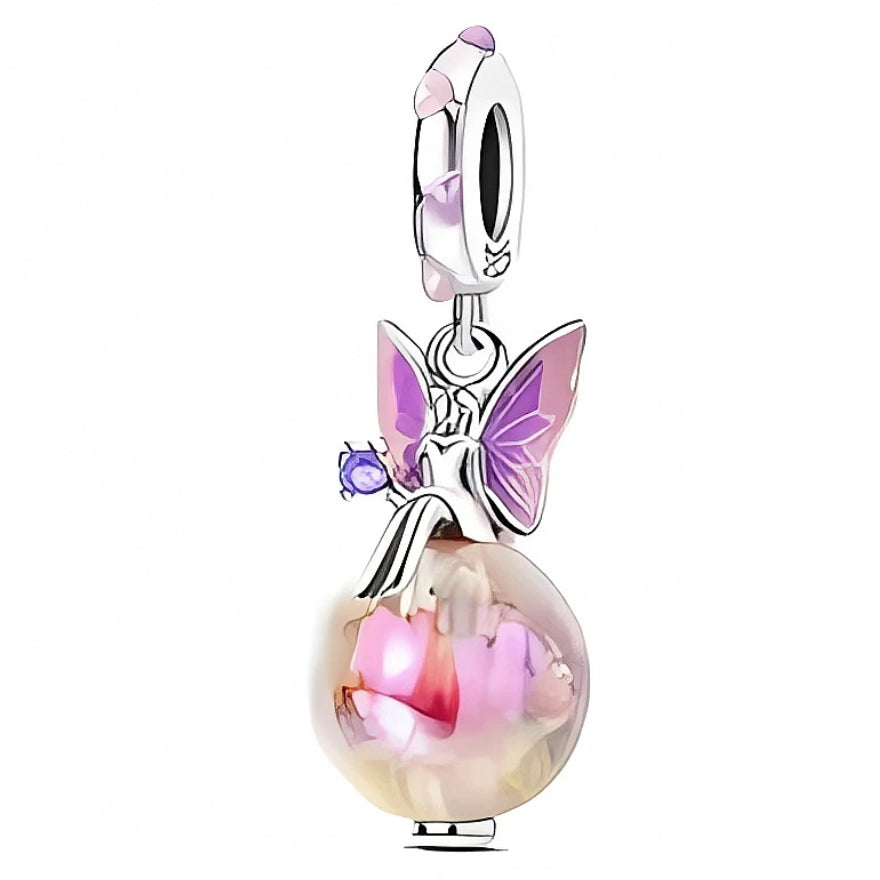 Ce charm met en scène une petite fée assise gracieusement sur une sphère irisée, en argent 925, dont les reflets roses et crème évoquent un jardin de fleurs capturé dans une bulle. Ses ailes émaillées dans des tons violets et roses, ainsi que la pierre violette qu’elle tient dans la main, apportent une touche magique parfaite pour illuminer un bracelet ou un collier.
