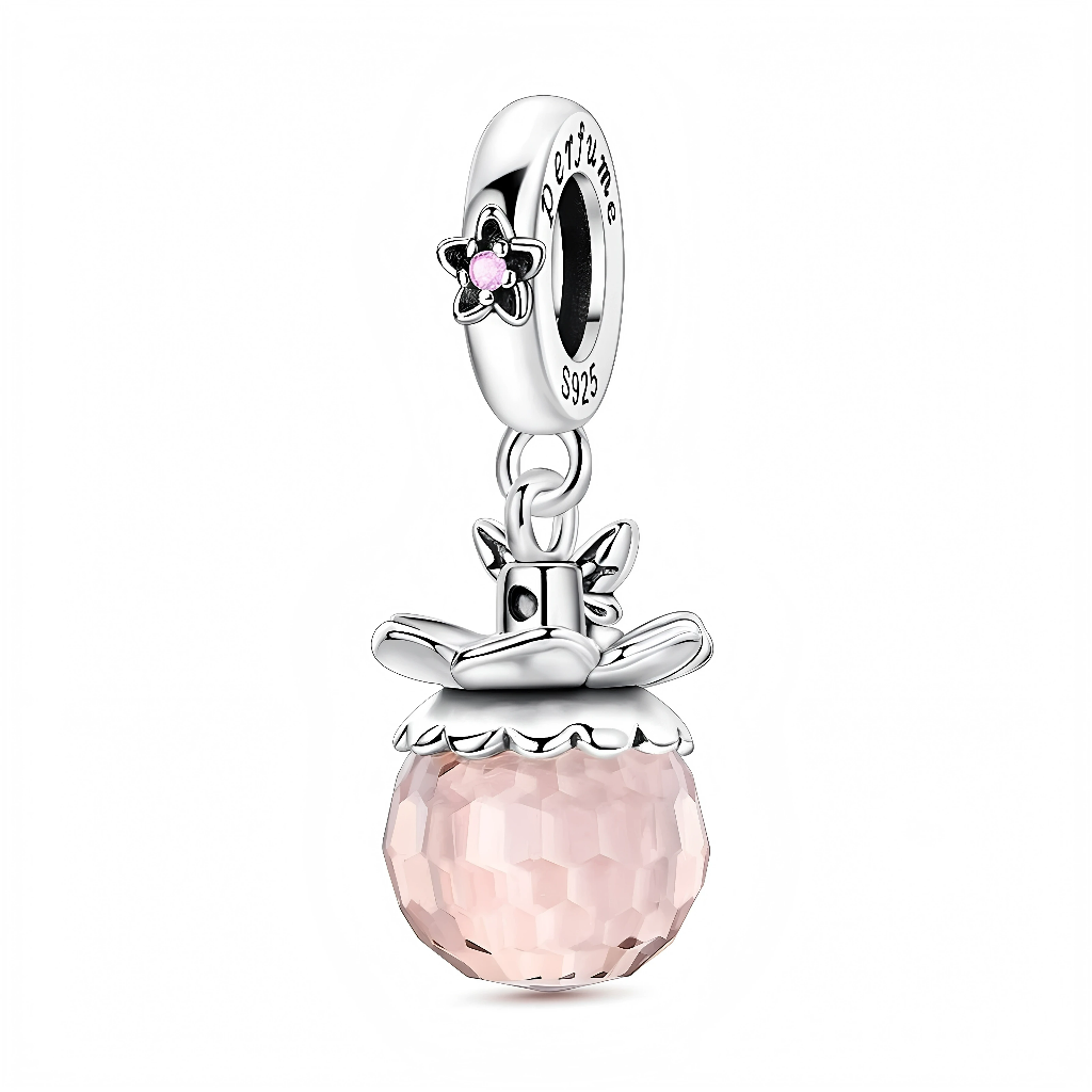 Ce charm pendentif en argent 925 représente un élégant flacon de parfum, composé d’une boule en cristal rose facetté qui capte magnifiquement la lumière, surmontée d’un bouchon argenté en forme de nœud stylisé. La bélière est décorée d’une petite fleur sertie d’un cristal rose et gravée du mot « perfume », pour une touche ultra féminine.