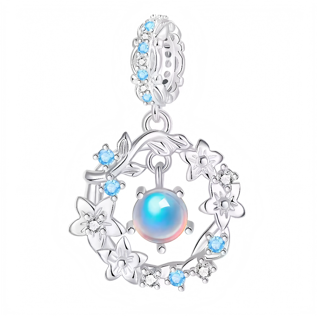 Ce charm en argent 925 expose une perle lune iridescente aux reflets arc-en-ciel au centre d’une couronne florale ajourée aux pétales délicats et branchages entrelacés, pavés de zircons bleus scintillants sur l’ensemble du cadre. Il irradie douceur lunatique et grâce florale, idéal pour un bracelet romantique ou mystique.

Caractéristiques :

Matière : Argent 925, perle lune synthétique, zircons bleus
Design : Couronne fleurs autour perle centrale pavée, bélière ajourée
Style : Lunaire floral enchanté, pour