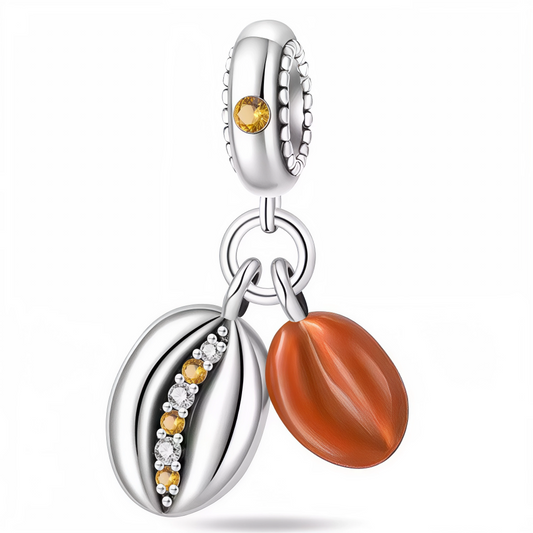 Offrez à votre bracelet une pointe d’originalité et de chaleur avec ce charm “Graines de Café Duo” en argent 925 ! Il associe une graine de café argentée ornée de pierres jaunes et blanches scintillantes à une graine de café émaillée marron, dans un esprit à la fois chic et gourmand. La bélière, décorée d’un cristal jaune, complète ce design raffiné : idéal pour les amoureux du café et des petits plaisirs du quotidien.