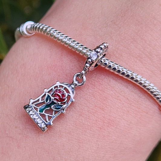Revivez la magie de La Belle et la Bête avec ce charm pendentif exquis mettant en vedette la célèbre rose enchantée. Fabriqué en argent sterling 925, ce pendentif capture la beauté et la mystique de la rose sous une cloche de verre avec des détails raffinés et une finition éclatante. Parfait pour les fans de Disney et les amateurs de cette romance intemporelle, ce charm ajoutera une touche élégante et rêveuse à votre bracelet ou collier.