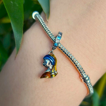Incarnez l'élégance artistique avec ce Charm - La Jeune Fille à la Perle, en argent sterling S925. Inspiré du célèbre tableau de Vermeer, ce charm est un hommage à la beauté intemporelle et à la délicatesse de cette œuvre d'art emblématique. Parfait pour les amateurs d'art et de culture, ce charm ajoute une touche de raffinement et de mystère à votre collection.