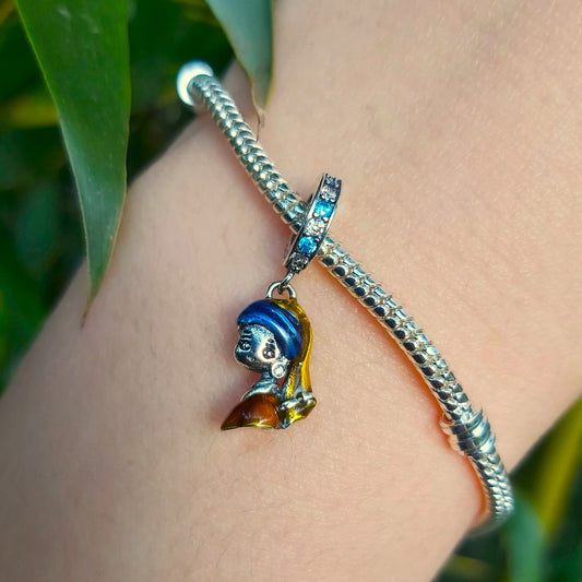 Incarnez l'élégance artistique avec ce Charm - La Jeune Fille à la Perle, en argent sterling S925. Inspiré du célèbre tableau de Vermeer, ce charm est un hommage à la beauté intemporelle et à la délicatesse de cette œuvre d'art emblématique. Parfait pour les amateurs d'art et de culture, ce charm ajoute une touche de raffinement et de mystère à votre collection.