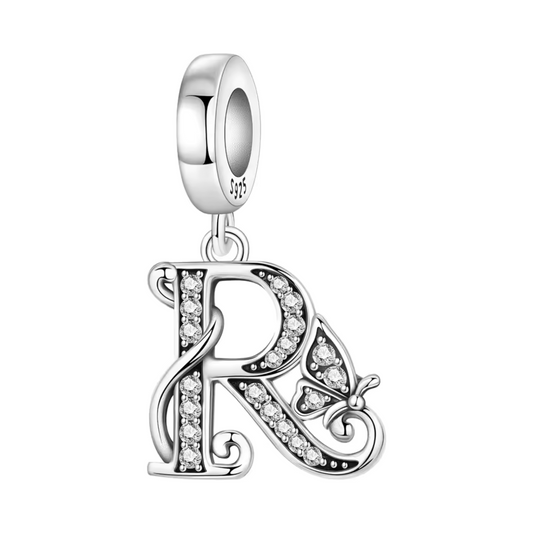 Ajoutez une touche personnelle et élégante à votre bracelet avec ce charm pendentif en argent 925 représentant la lettre "R". Son design raffiné est rehaussé de strass étincelants qui captent la lumière avec éclat, accompagné d’un petit papillon argenté, symbole de transformation et de liberté. Un bijou plein de sens, idéal à offrir ou à porter au quotidien.