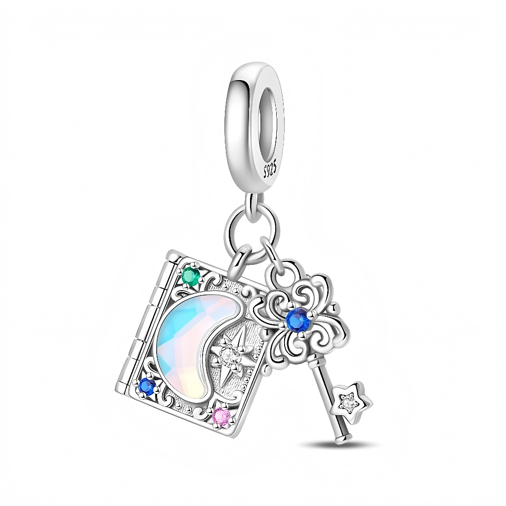 Ce charm double pendant en argent 925 met en scène un petit livre orné d’un croissant de lune opalescent et d’une étoile scintillante, encadrés de cristaux vert, bleu et rose sur la couverture finement gravée. Une clé féerique aux volutes délicates, sertie d’un cristal bleu au centre et terminée par une étoile, pend à côté du livre pour symboliser l’ouverture des secrets et des rêves.

Caractéristiques :

-Matière : Argent 925 avec pierre opalescente et zirconias colorés.
-Design : Livre magique décoré d’un