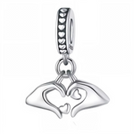 Ce charm pendentif en&nbsp;argent&nbsp;925 représente deux mains stylisées formant un cœur, avec un petit cœur ajouré au centre et un autre suspendu en dessous pour un effet tendre et raffiné. La bélière est décorée d’une rangée de petits cœurs ajourés et gravée « S925 », idéale pour ajouter une touche romantique à un bracelet à charms ou à un collier.

Caractéristiques :

Matière : Argent 925 (S925)
Design : Deux mains minimalistes qui dessinent un cœur, complétées par deux petits cœurs pendants et un anne