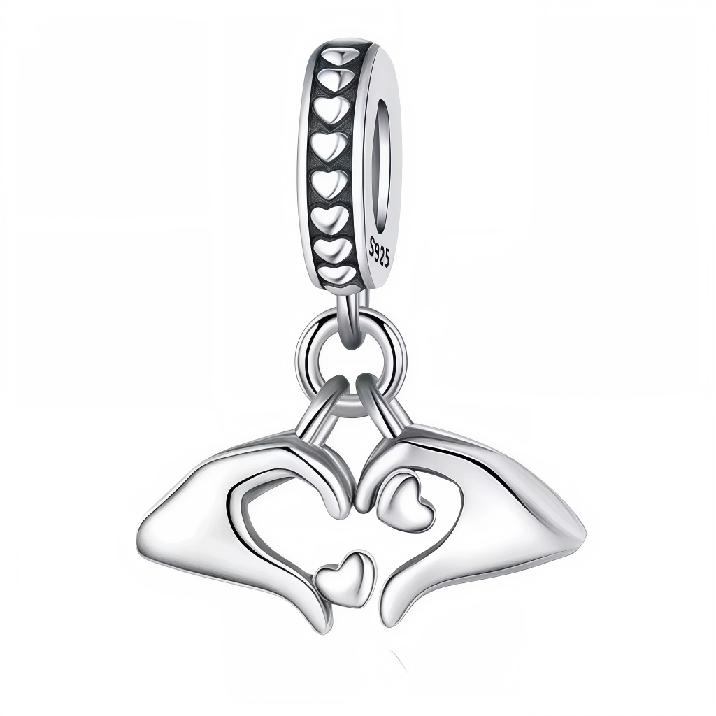 Ce charm pendentif en&nbsp;argent&nbsp;925 représente deux mains stylisées formant un cœur, avec un petit cœur ajouré au centre et un autre suspendu en dessous pour un effet tendre et raffiné. La bélière est décorée d’une rangée de petits cœurs ajourés et gravée « S925 », idéale pour ajouter une touche romantique à un bracelet à charms ou à un collier.

Caractéristiques :

Matière : Argent 925 (S925)
Design : Deux mains minimalistes qui dessinent un cœur, complétées par deux petits cœurs pendants et un anne