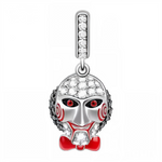 Ce pendentif reprend la silhouette glaçante du célèbre masque: yeux rouges cerclés de noir, spirales rouges sur les joues et nœud papillon laqué rouge. Le front est pavé de micro‑zircons étincelants tandis que la bélière alignée de pierres apporte une brillance continue. Une pièce statement pour les fans de films d’horreur et les compositions thématiques d’octobre.