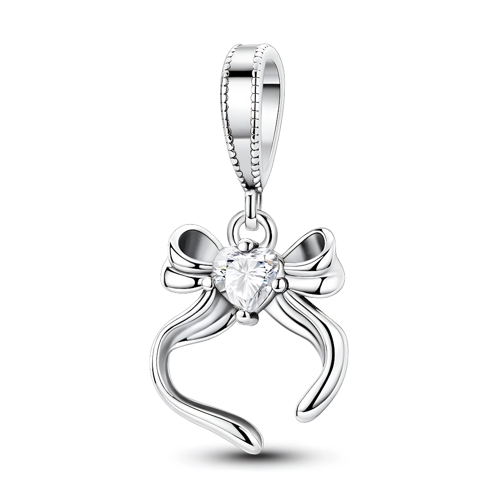 Ce charm pendentif en argent se compose d’un élégant nœud ruban dont les extrémités ondulées encadrent un cristal clair en forme de cœur, parfaitement mis en avant au centre. Sa ligne fine et féminine en fait un bijou discret et raffiné, idéal pour symboliser un cadeau, un lien affectif ou une promesse.