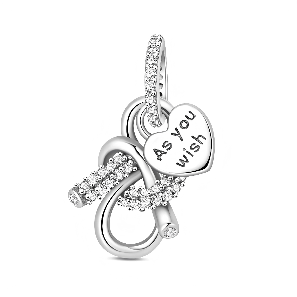 Le design met en scène un grand nœud ouvert en argent dont les courbes se croisent comme un symbole d’infini, entièrement pavé de zircons scintillants pour un rendu très lumineux. Au centre du nœud se balance un cœur lisse portant l’inscription « As you wish », message romantique qui évoque la dévotion, l’écoute et le désir de combler l’être aimé. La bélière, elle aussi sertie de pierres, prolonge l’effet bijou de luxe et permet de porter ce pendentif aussi bien sur un bracelet que sur un collier.