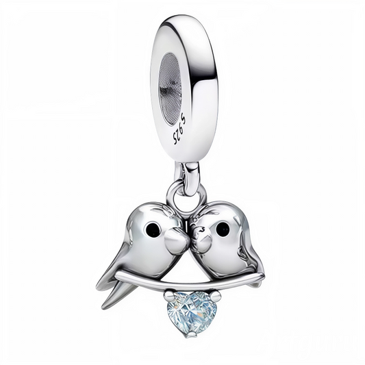 Ajoutez une touche de tendresse et de poésie à votre collection avec ce charm pendentif en argent 925 représentant deux petits oiseaux se blottissant l’un contre l’autre sur une branche délicate. Symbole d’amour, de complicité et de douceur, ce bijou raffiné est sublimé par un petit cœur brillant incrusté dans la branche. Un accessoire romantique et élégant, idéal pour célébrer les liens précieux.