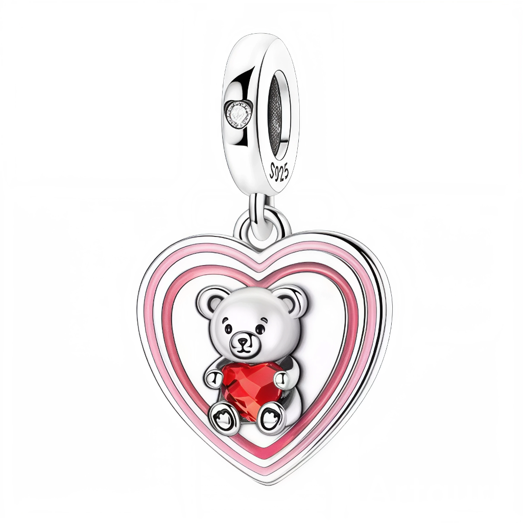 Ce charm ultra tendre met en avant un adorable ourson argenté enlacé autour d’un cœur rouge éclatant façon cristal, symbole d’amour profond et de protection. Le tout est encadré par un grand cœur aux dégradés de rose, rappelant la douceur, le réconfort et, si tu le souhaites, l’esprit d’Octobre Rose tout en restant très romantique. La bélière S925 lisse est rehaussée d’un petit strass en forme de cœur, pour une finition élégante et lumineuse.