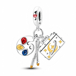 Suspendus à une bélière gravée S925 et décorée d’un petit cœur rouge, une palette de peintre argentée affiche trois touches d’émail rouge, jaune et bleu, accompagnée de deux pinceaux finement détaillés. À ses côtés, un carnet rectangulaire est embelli de motifs lune et étoiles dorés, symbolisant l’inspiration, l’imagination et les projets à venir. L’ensemble forme un bijou dynamique qui évoque à la fois l’art, l’écriture et le pouvoir de créer sa propre destinée.