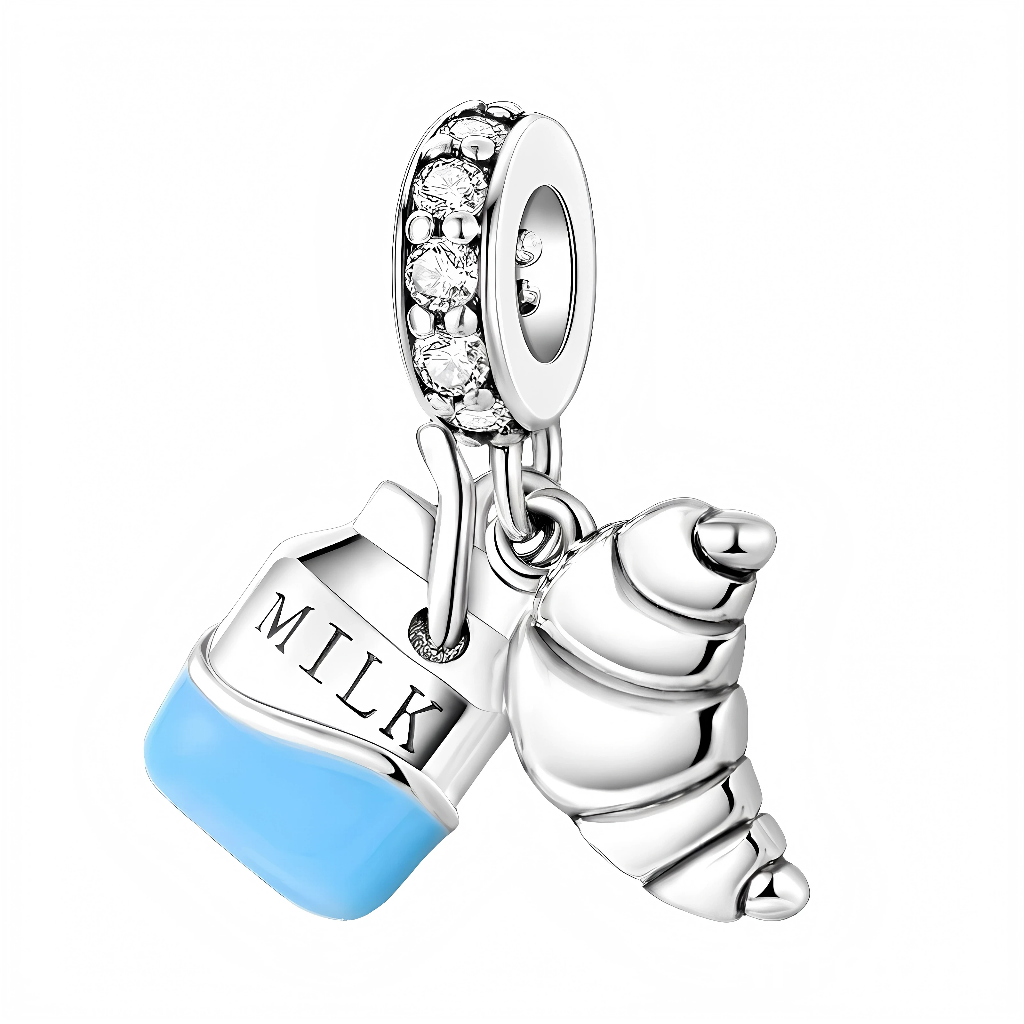 La bélière sertie de zircones scintillantes porte deux breloques mobiles : le carton de lait gravé « MILK » avec base bleue émaillée, et un croissant détaillé qui évoque une viennoiserie fraîchement sortie du four. L’ensemble crée un charm ludique et irrésistible, parfait pour les amoureux des petits‑déjeuners à la française.zarabelas+2