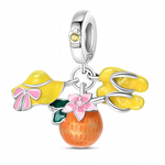 Ce charm pendentif en argent 925 réunit trois breloques estivales : un chapeau de soleil jaune orné d’un nœud rose, une paire de sandales jaunes et une orange juteuse décorée d’une fleur rose et de feuilles vertes. La bélière est agrémentée d’une petite fleur sertie d’un zircon jaune, rappelant la chaleur du soleil.