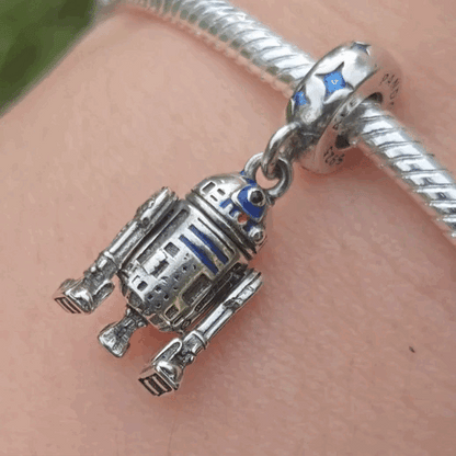 Ajoutez une touche d'aventure galactique à votre collection avec ce charm représentant R2-D2, le droïde astromécano emblématique de Star Wars. Conçu en argent sterling S925, ce charm capture avec précision les détails distinctifs et le design emblématique de R2-D2.