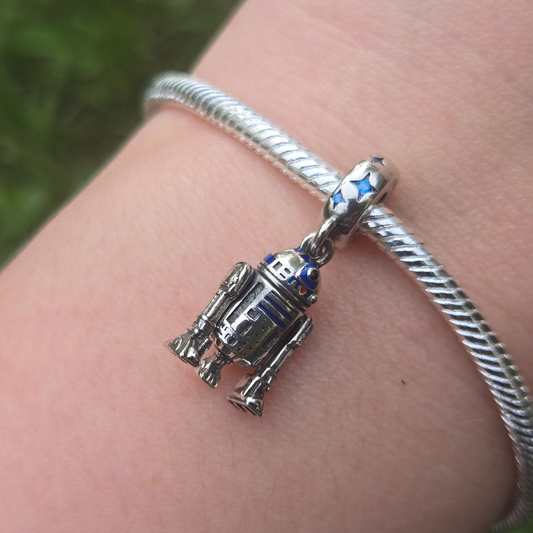 Ajoutez une touche d'aventure galactique à votre collection avec ce charm représentant R2-D2, le droïde astromécano emblématique de Star Wars. Conçu en argent sterling S925, ce charm capture avec précision les détails distinctifs et le design emblématique de R2-D2.