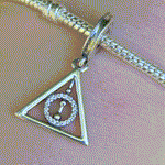 Affichez votre fascination pour les symboles légendaires de la saga Harry Potter avec ce charm pendentif Reliques de la Mort en argent sterling 925. Représentant le célèbre triangle des Reliques de la Mort (la Baguette de Sureau, la Pierre de Résurrection et la Cape d'Invisibilité), ce charm est un incontournable pour les fans de la magie et des mystères de Poudlard. Compatible avec les bracelets Pandora, ce pendentif ajoutera une touche mystique à votre collection.