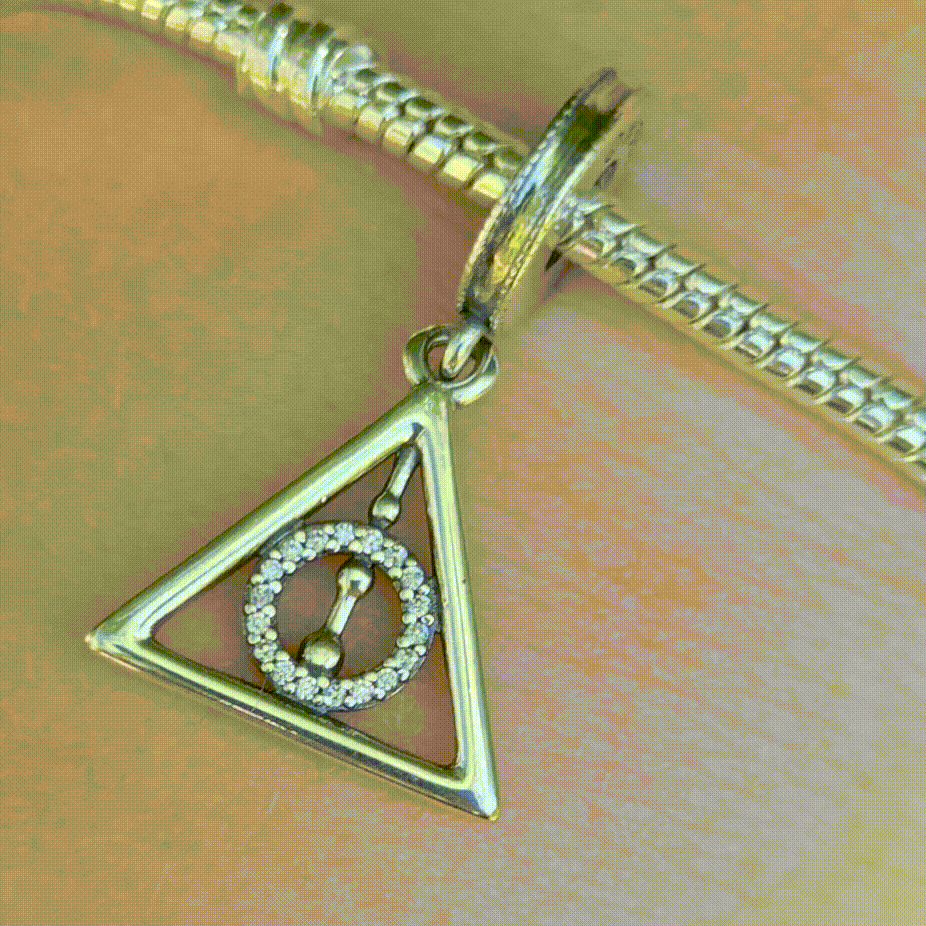 Affichez votre fascination pour les symboles légendaires de la saga Harry Potter avec ce charm pendentif Reliques de la Mort en argent sterling 925. Représentant le célèbre triangle des Reliques de la Mort (la Baguette de Sureau, la Pierre de Résurrection et la Cape d'Invisibilité), ce charm est un incontournable pour les fans de la magie et des mystères de Poudlard. Compatible avec les bracelets Pandora, ce pendentif ajoutera une touche mystique à votre collection.