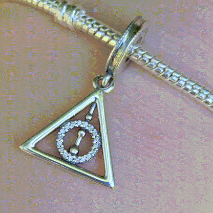 Affichez votre fascination pour les symboles légendaires de la saga Harry Potter avec ce charm pendentif Reliques de la Mort en argent sterling 925. Représentant le célèbre triangle des Reliques de la Mort (la Baguette de Sureau, la Pierre de Résurrection et la Cape d'Invisibilité), ce charm est un incontournable pour les fans de la magie et des mystères de Poudlard. Compatible avec les bracelets Pandora, ce pendentif ajoutera une touche mystique à votre collection.
