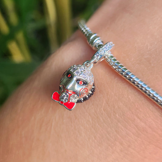 Ajoutez une touche de suspense et de mystère à votre collection avec ce charm représentant Jigsaw, le redoutable personnage de la franchise Saw. Conçu en argent sterling S925, ce charm capture l'essence sinistre du maître des jeux, avec son visage emblématique et ses célèbres roues dentées.

Le design détaillé de Jigsaw, avec ses traits reconnaissables et son sourire inquiétant, est parfait pour les amateurs de films d'horreur et les fans de la série culte.