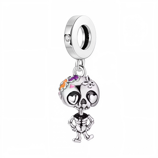 Célébrez la vie et la couleur avec ce charm inspiré de la tradition mexicaine du Día de los Muertos ! Réalisé en argent 925, ce petit squelette affiche un large sourire et une tête décorée de motifs floraux orange, rose et violet, tandis que les yeux en forme de cœur rappellent la joie et la tendresse de cette fête. Les finitions émaillées et la pierre scintillante sur la bélière apportent luminosité et raffinement à la pièce, parfaite pour agrémenter votre bracelet d’une note festive et symbolique.