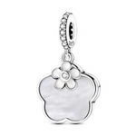 Ce charm pendentif en argent 925 met en valeur un grand motif trèfle à quatre feuilles serti d’une nacre blanche lumineuse, surmonté d’une petite fleur stylisée en métal poli. Le centre de la fleur est orné d’un zircon scintillant, tandis que l’anneau supérieur, pavé de petites pierres brillantes, apporte une touche d’éclat supplémentaire dans l’esprit des charms floraux en nacre très prisés en joaillerie contemporaine.