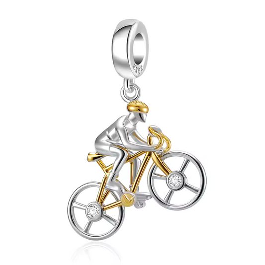 Célébrez la légende du cyclisme avec ce charm pendentif en argent 925 représentant un vélo élégant, accompagné d’un petit personnage en argent et de subtiles touches dorées. Inspiré par l’énergie et la passion du Tour de France, ce bijou est un hommage raffiné aux amateurs de deux-roues et aux grandes épopées sportives.