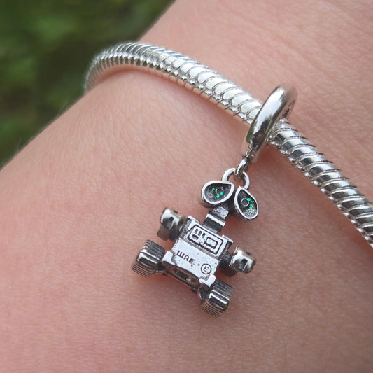 Apportez une touche de magie cinématographique à votre collection avec ce Charm - WALL-E, fabriqué en argent sterling S925. Inspiré par le célèbre personnage du film d’animation de Pixar, ce charm représente WALL-E, le petit robot au grand cœur, qui nous rappelle l'importance de la préservation de notre planète et de l'amour.