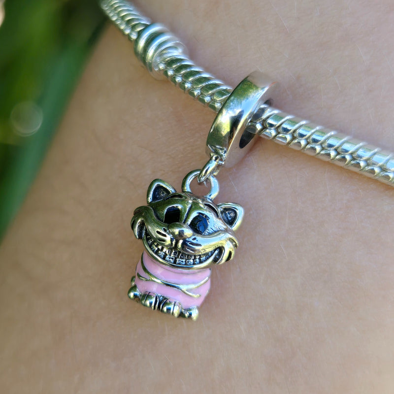 Ce charm pendentif en argent 925 capture le Chat du Cheshire d'Alice au Pays des Merveilles&nbsp;aux rayures rose bonbon psychédéliques vives, sourire malicieux flottant dominant, yeux pétillants espiègles. Il symbolise folie joyeuse, énigmes sucrées et sagesse invisible du Pays des Merveilles.

Caractéristiques :

Matière : Argent 925 émail rose vif (rayures).
Design : Chat circulaire flottant, sourire oversized, contours noirs nets, crochet polyvalent.
Dimensions : 1,7 cm hauteur, pendante légère dynamiqu