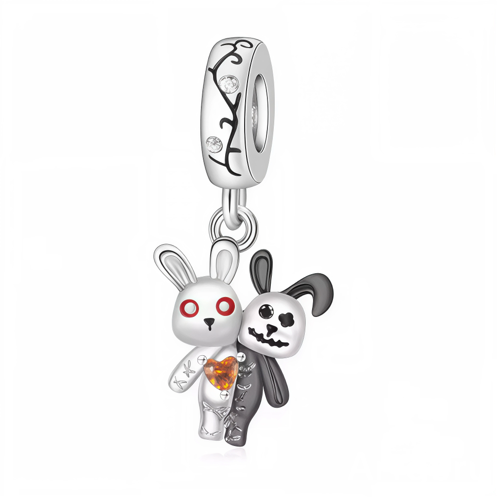Ce charm pendentif met en scène un duo irrésistible de lapins kawaii aux styles contrastés : un lapin blanc aux yeux rouges menaçants enlacé à un lapin noir squelettique, unis par un cœur orange fissuré pour un effet Halloween spooky-cute. Leurs corps stylisés en émail blanc et noir, avec des détails squelette transparents, évoquent une amitié au-delà de la vie, pleine de tendresse macabre. Suspendus à un anneau décoré de motifs floraux sertis de pierres claires, ils balancent avec malice au poignet.