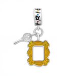 Ce charm pendentif nostalgique recrée l’appartement iconique de Friends avec le cadre de porte orange mustard enamel emblématique (saison 1), suspendu à une clé dorée réaliste symbolisant l’accès au Central Perk et aux aventures des six amis. L’anneau supérieur multicolore “F R I E N D S” avec points colorés assure une fixation Pandora-style parfaite en argent sterling poinçonné « S925 ». Les détails précis du cadre violet avec moulures capturent l’atmosphère cosy de la série, parfait pour les fans qui veul