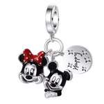 Ce charm pendentif célèbre la joie et la tendresse éternelles du couple emblématique Mickey et Minnie Mouse. Façonnés en argent fin, leurs visages expressifs et pleins de malice sont sublimés par des détails en émail noir et rouge, avec le célèbre nœud à pois de Minnie et un motif “Happy Day” gravé sur une médaille argentée. Les petites étoiles cristallines sur la médaille accentuent la magie du design et l’univers enchanté de Disney.