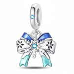 Ce charm pendentif en argent 925 représente un élégant nœud de ruban agrémenté d’un flocon de neige central, souligné de dégradés bleus givrés. Il évoque la magie des cadeaux de Noël, des paysages enneigés et des instants chaleureux partagés en hiver.

Caractéristiques :
-Matière : Argent 925/1000 massif, finition brillante, ruban partiellement émaillé de bleu et flocon orné d’un cristal synthétique bleu au centre.
-Design : Charm pendentif composé d’une bélière lisse décorée d’une petite pierre bleue, d’un