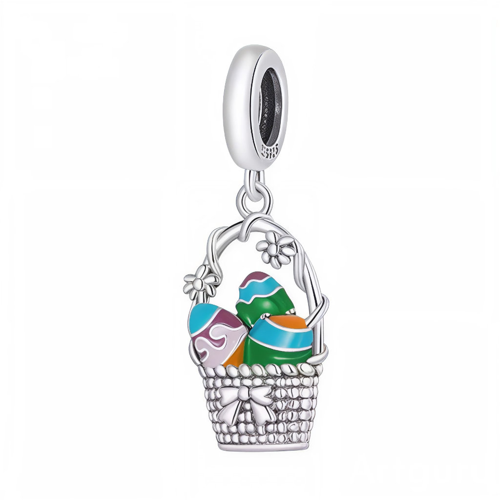 Ce charm pendentif évoque la joie de Pâques avec un panier tressé en argent sterling rempli de trois œufs émaillés aux couleurs vives : vert, bleu-violet et orange, décorés de motifs festifs. Des petites fleurs argentées ornent les anses courbées, ajoutant une touche printanière et délicate à cette composition pleine de surprises. L’anneau supérieur permet une suspension gracieuse, idéal pour célébrer la saison avec éclat.