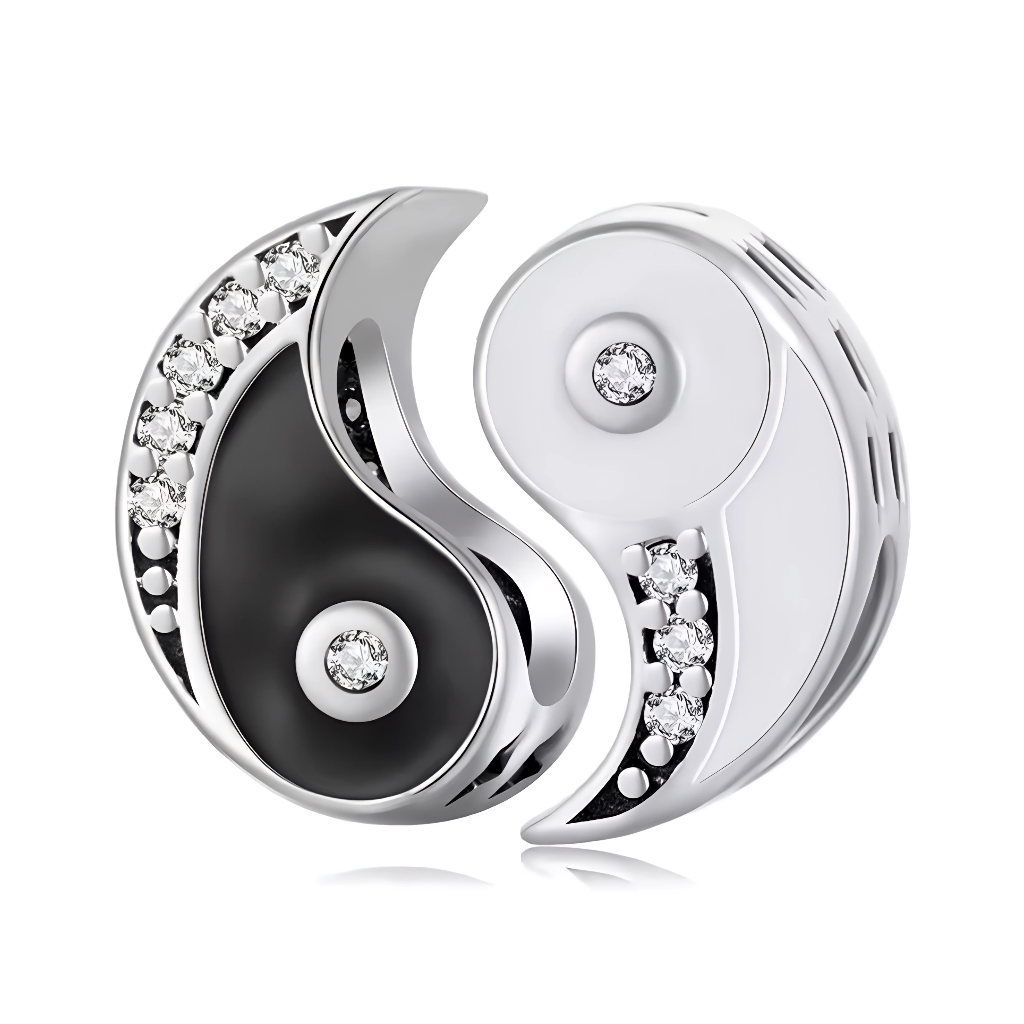 Ce charm pendentif emblématique arbore le symbole du Yin Yang en noir et blanc contrastés, avec un émail noir lustré d’un côté et un argent poli de l’autre, soulignant l’harmonie des opposés. Des zircons étincelants serti le long des courbes ondulées et au centre de chaque moitié ajoutent une brillance mystique et raffinée. L’anneau supérieur intégré permet une fixation fluide sur les bracelets à charms.