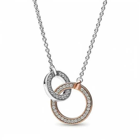 Ajoutez une touche d’originalité discrète à votre style quotidien avec ce collier Cercles Entrelacés. Conçu en argent 925/1000e et métal doré à l’or rose, ce bijou élégant présente deux cercles mobiles décorés de rangées scintillantes au centre, encadrées de micro-détails sertis grain. Son design bicolore et harmonieux rehausse subtilement toutes les tenues. Réglable sur deux longueurs, il s’adapte facilement à votre style, qu’il soit chic ou décontracté.