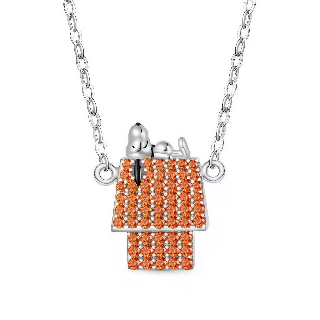 Ce collier capture la pose iconique de Snoopy, détendu sur sa maisonnette. Le toit et la façade sont entièrement pavés de pierres orange lumineuses qui apportent éclat et relief, tandis que Snoopy en argent poli crée un contraste élégant. Un bijou pop‑culture chic, parfait pour illuminer une tenue ou offrir à un fan des Peanuts.