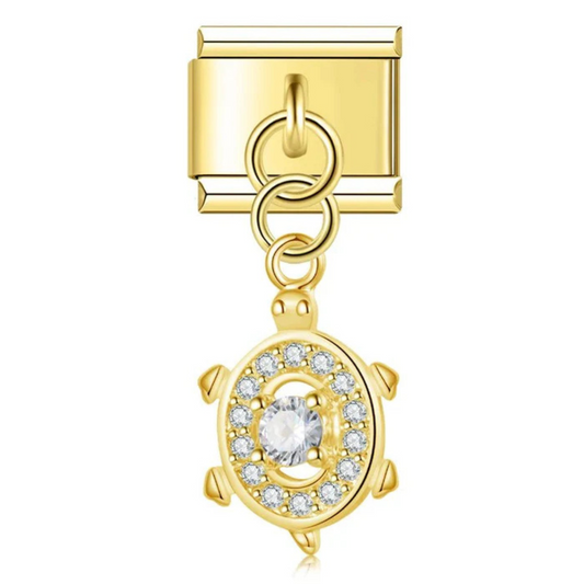 Ce charm italien pendentif représente une jolie tortue, symbole de sagesse et de longévité. Avec sa finition dorée éclatante, il est fabriqué en acier inoxydable de haute qualité pour offrir robustesse et élégance. Facile à fixer, il s’adapte parfaitement à nos bracelets composés de 17 maillons extensibles et réglables, convenant à toutes les tailles de poignet. Compatible avec tous nos charms italiens, ce bijou raffiné est idéal pour personnaliser votre bracelet avec une touche marine et intemporelle.