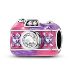 Ce charm en argent 925 prend la forme d’un appareil photo vintage, habillé d’un émail dégradé rose et violet parsemé de petits cœurs en relief. Une grande pierre claire ronde occupe la place de l’objectif, tandis que deux petits cristaux brillent sur le « flash » pour un effet ultra scintillant.