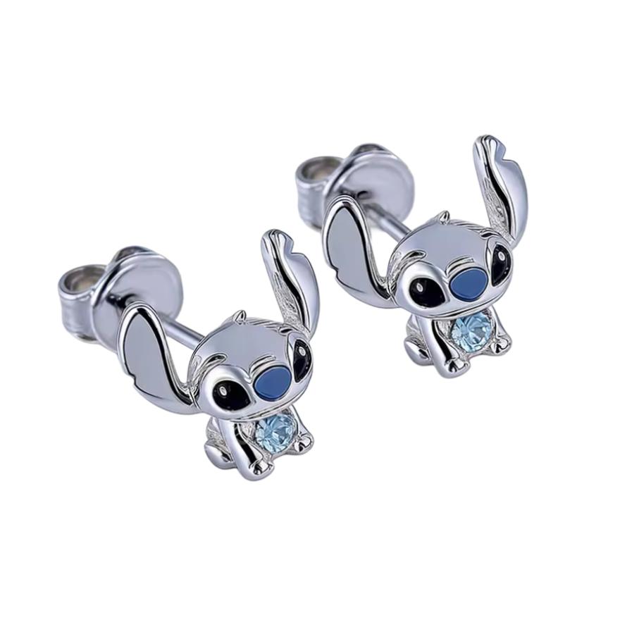 Ces boucles d’oreilles pendantes raffinées mettent en scène une petite créature bleue espiègle au pelage argenté doux, avec de grands yeux ronds pétillants et des oreilles démesurées levées en expression joyeuse. Chaque pendaison inclut un cristal bleu scintillant sur le ventre, ajoutant une touche magique et ludique. Les tiges en argent 925 assurent un port confortable et sécurisé.